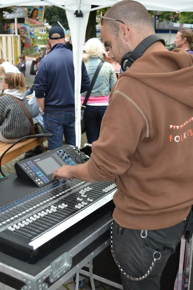 Philip working directly at a digital mixing console during an outdoor event.